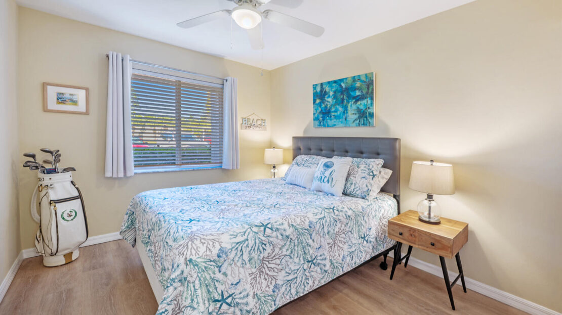 Bright bedroom with floral bedding and a large window.