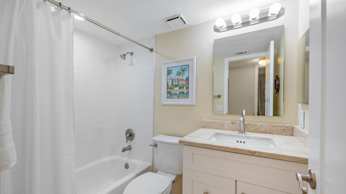 Bright and clean bathroom with a bathtub, toilet, and vanity.