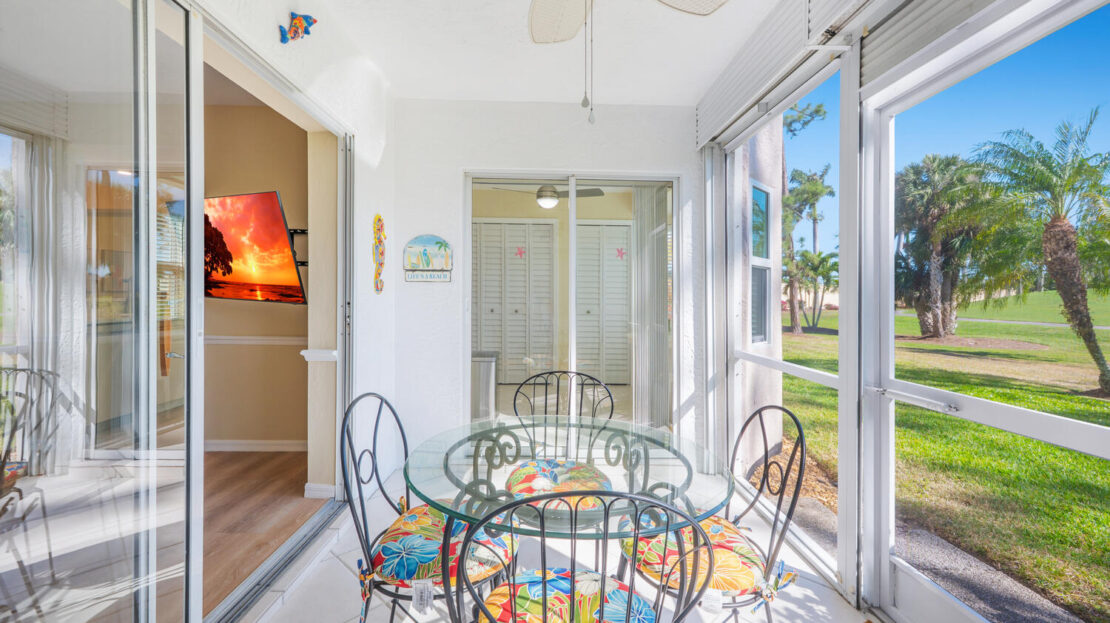 Sunlit dining area with glass table and colorful cushions.