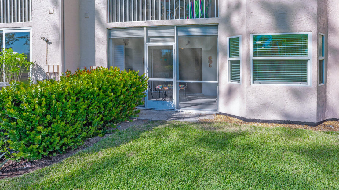 Entrance to a modern building with glass doors and green lawn.