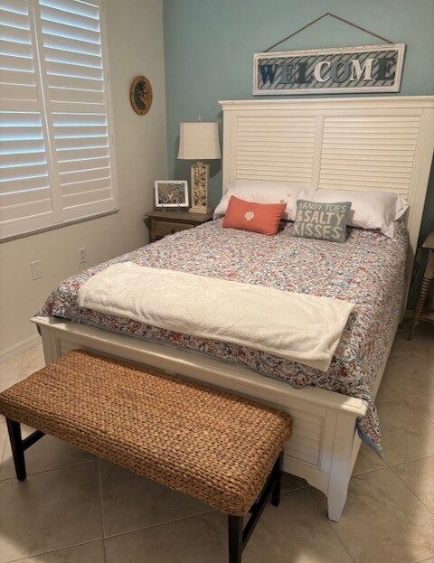 Cozy bedroom with a white wooden bed and a patterned bench at the foot.