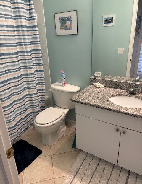 Clean bathroom with granite countertop and striped shower curtain.