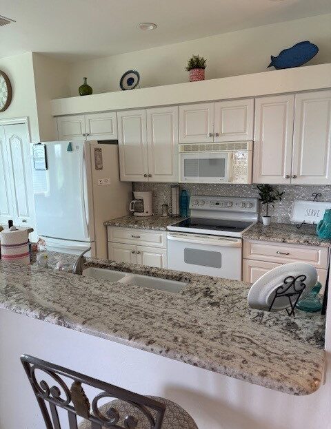 Bright kitchen with granite countertops and white cabinets.