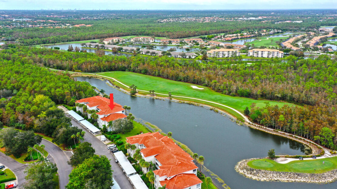 Aerial view of a winding river with red-roofed buildings and lush greenery.
