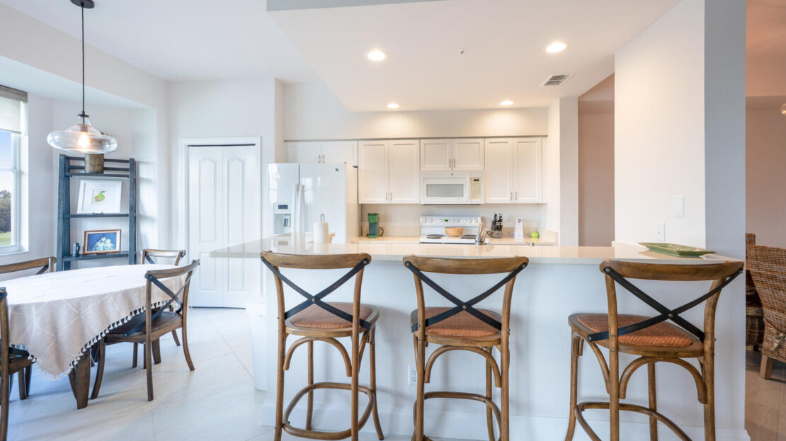 Modern kitchen with wooden bar stools and white cabinetry.