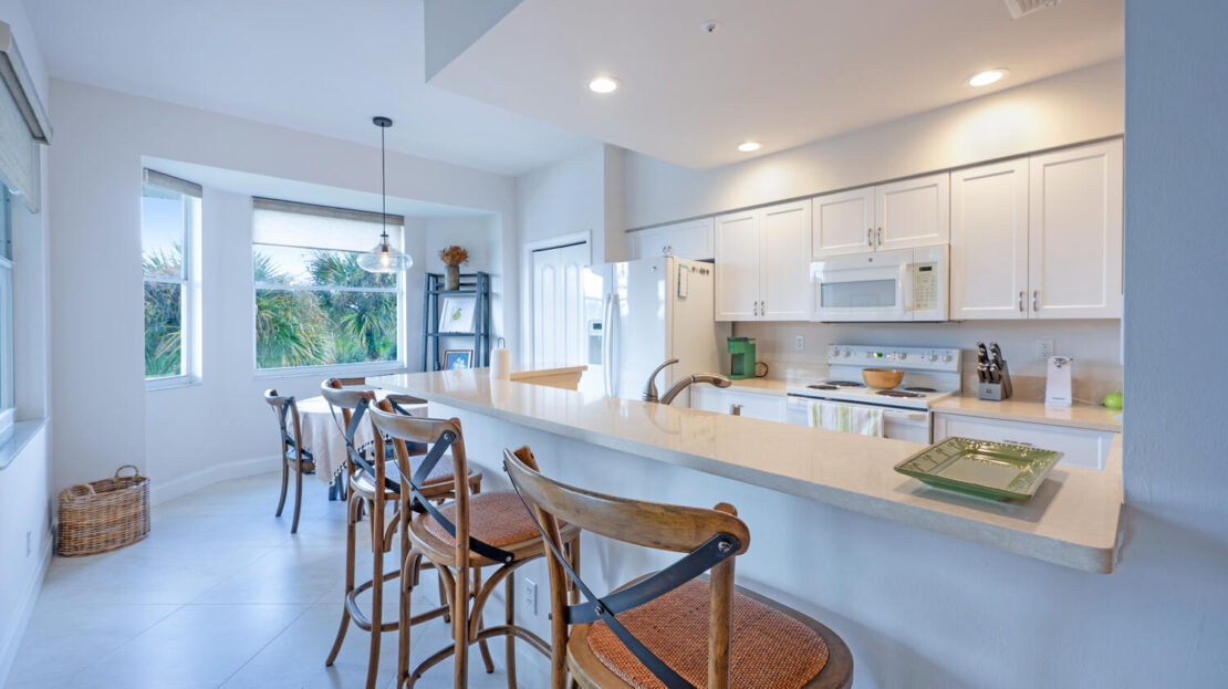 Bright, modern kitchen with a large island and wooden bar stools.