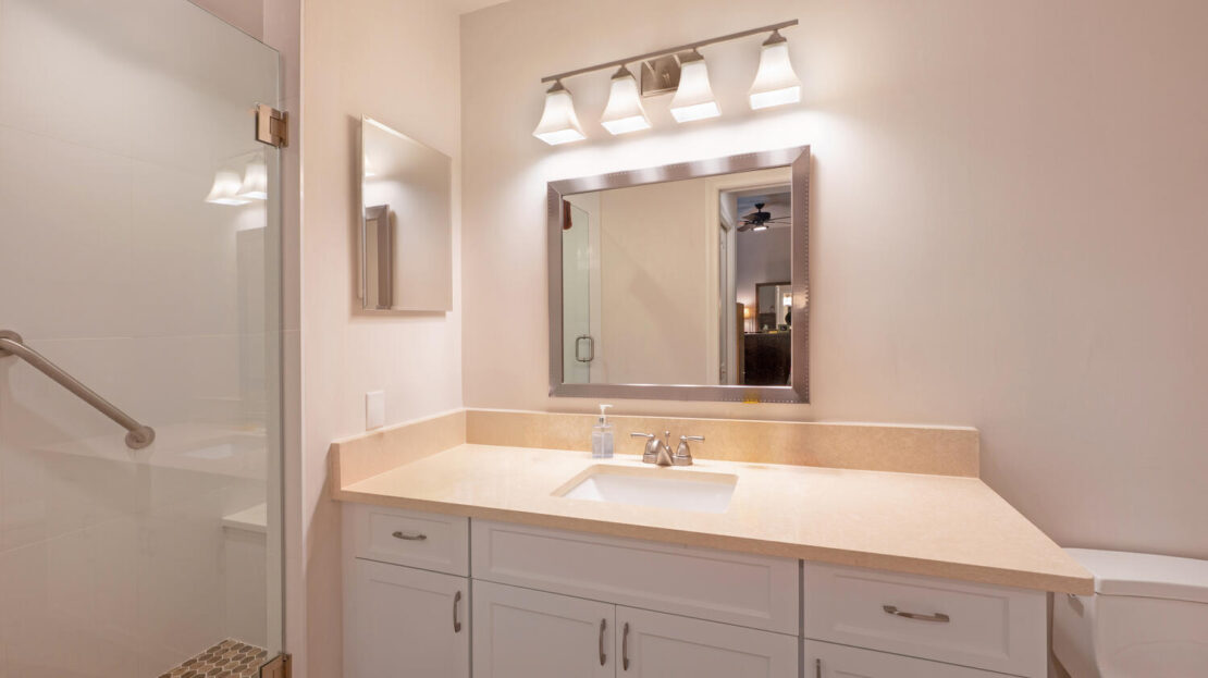 Modern bathroom sink area with large mirror and bright lighting.