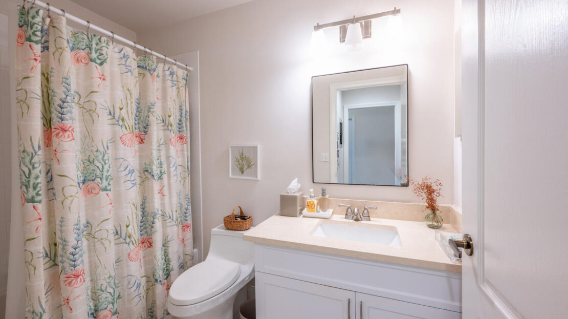 Bright bathroom with floral shower curtain and white vanity.