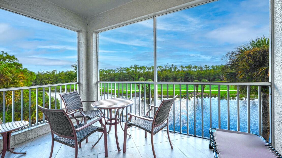 Outdoor seating area overlooking a pool and lush green landscape.