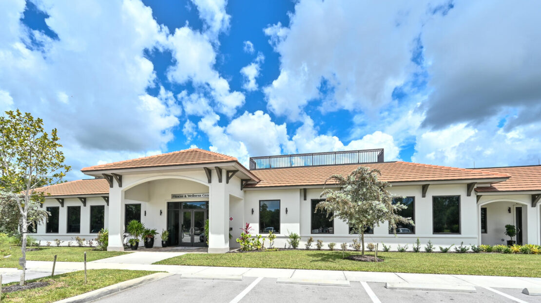 Modern clubhouse under a bright blue sky with scattered clouds.