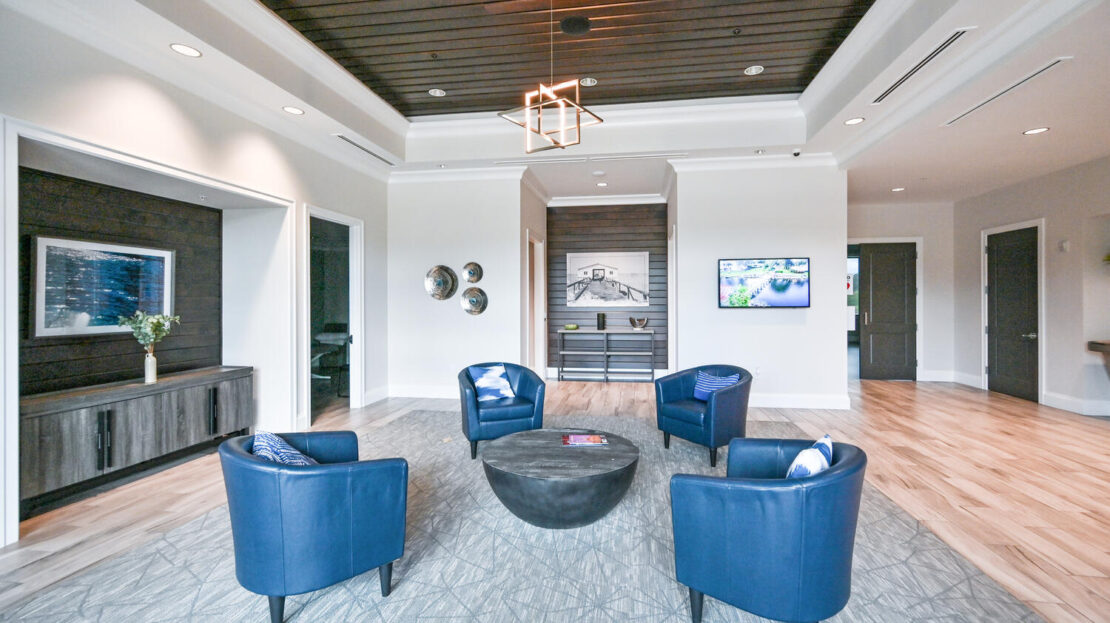 Modern living room with four blue chairs and a wooden ceiling.