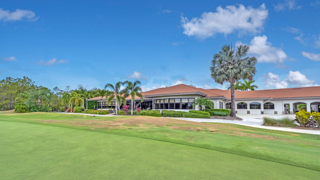 Luxurious golf clubhouse surrounded by palm trees under a blue sky.