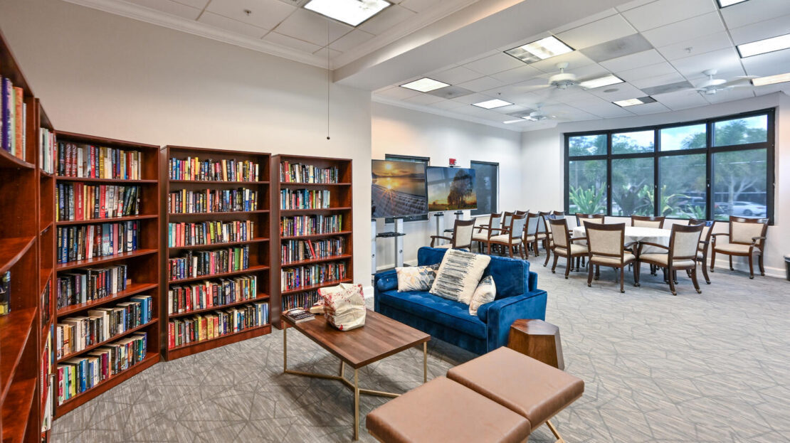 Cozy library corner with bookshelves, blue couch, and seating area.