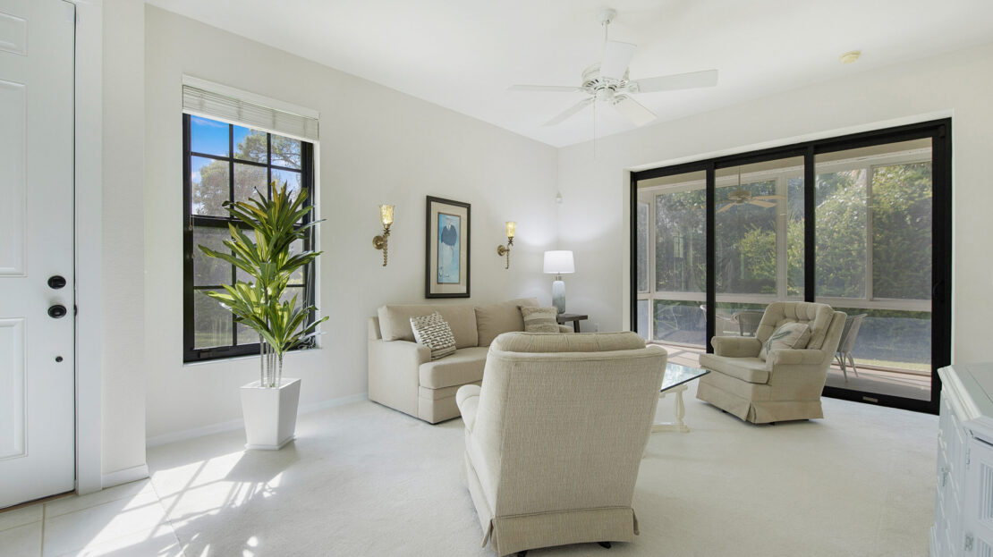 Bright living room with large windows and cozy seating.
