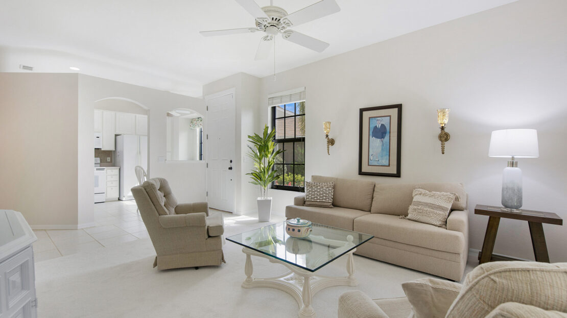 Bright, modern living room with beige furniture and glass coffee table.