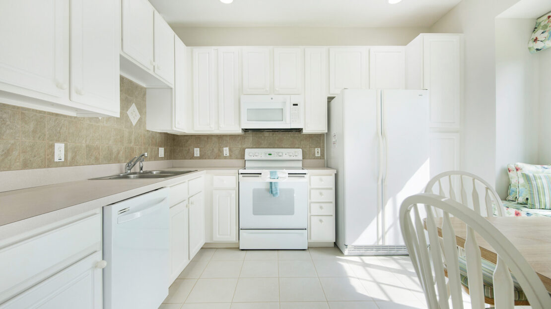Bright modern white kitchen with appliances and ample storage.