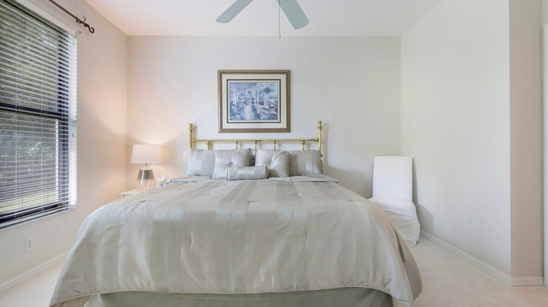 Bright bedroom with a large bed, white bedding, and a ceiling fan.
