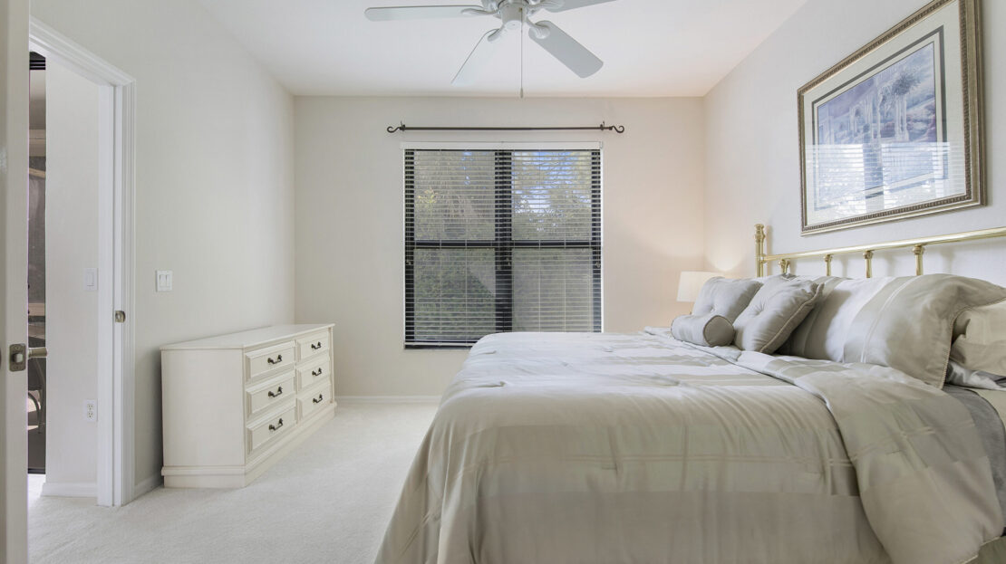Bright bedroom with neutral tones and large window.