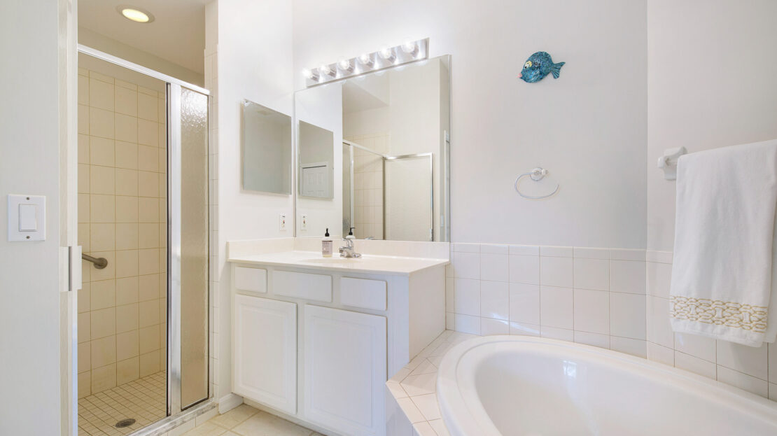 Bright bathroom with white vanity, bathtub, and glass shower.