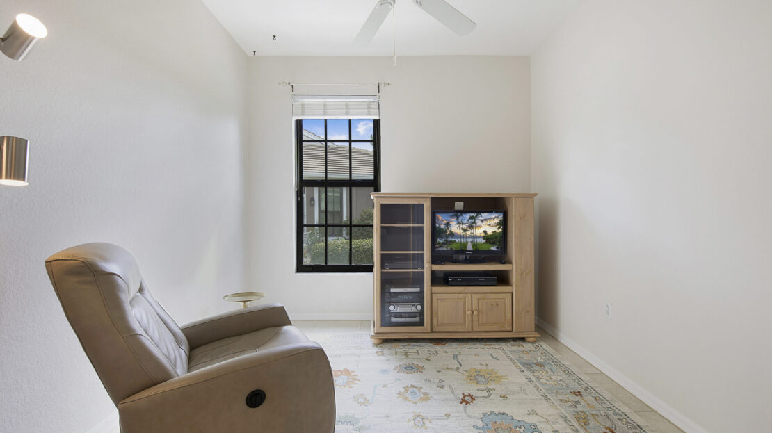 Minimalist living room with recliner, wooden TV cabinet, and patterned rug.