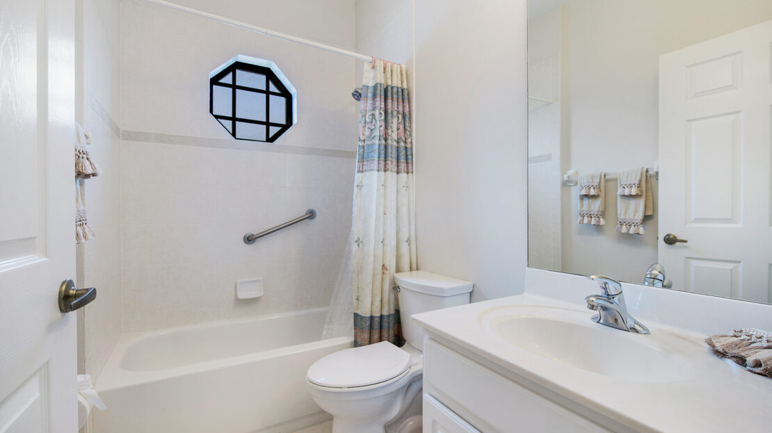 Bright bathroom with white fixtures and a decorative window.