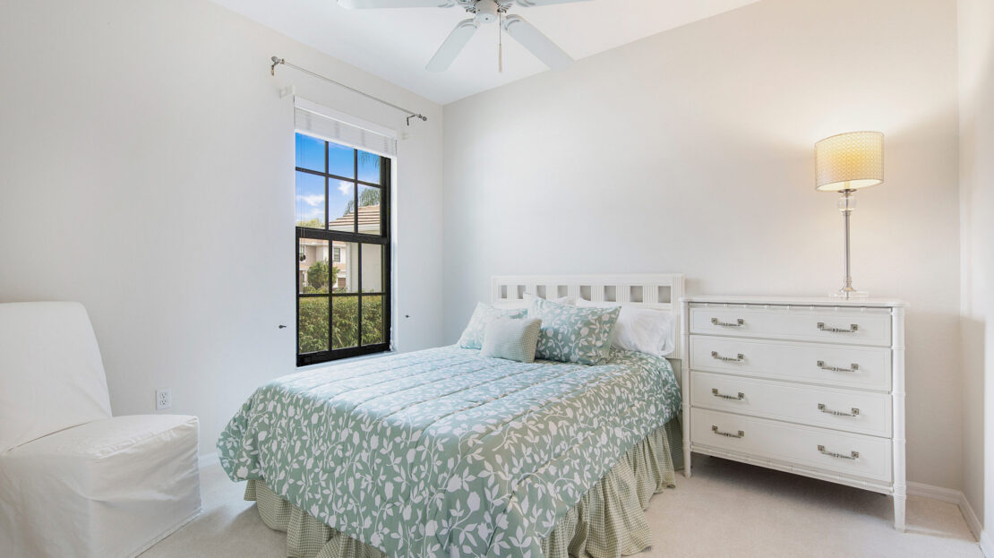 Bright, cozy bedroom with floral bedding and white furniture.