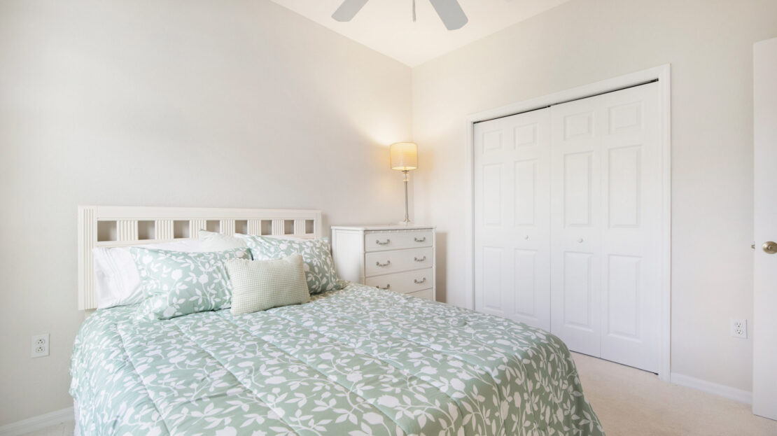 Bright bedroom with floral bedding and white furniture.