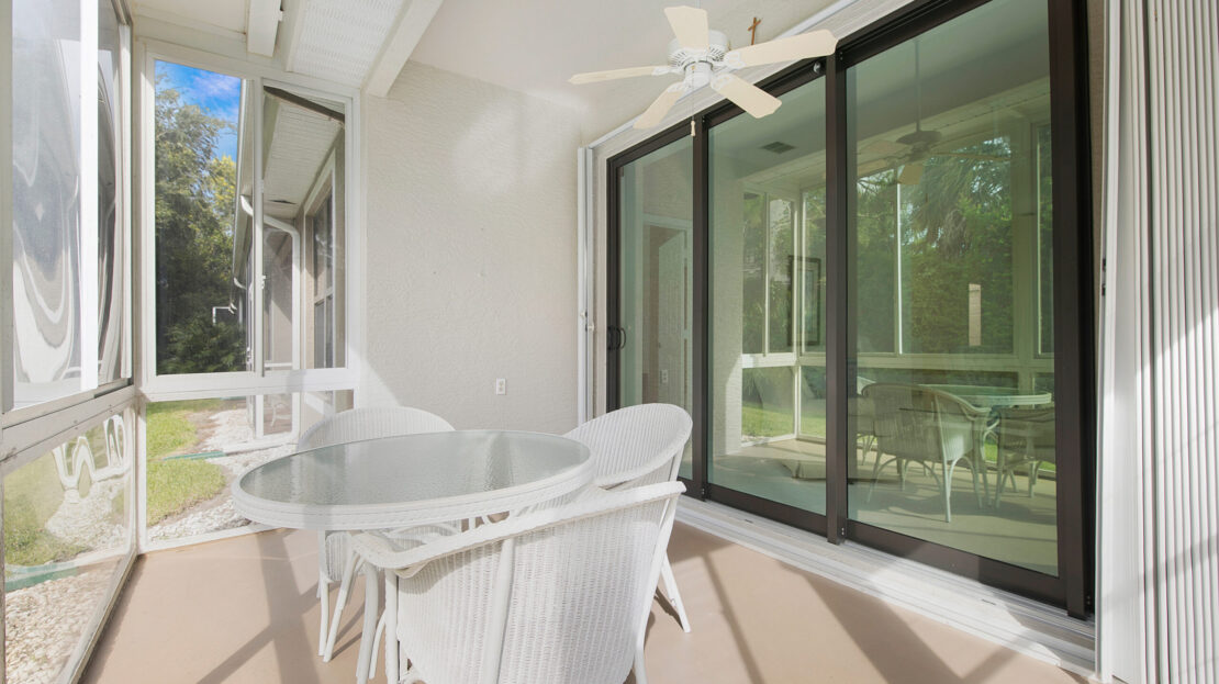 Bright patio with a white wicker table and chairs set under ceiling fans.