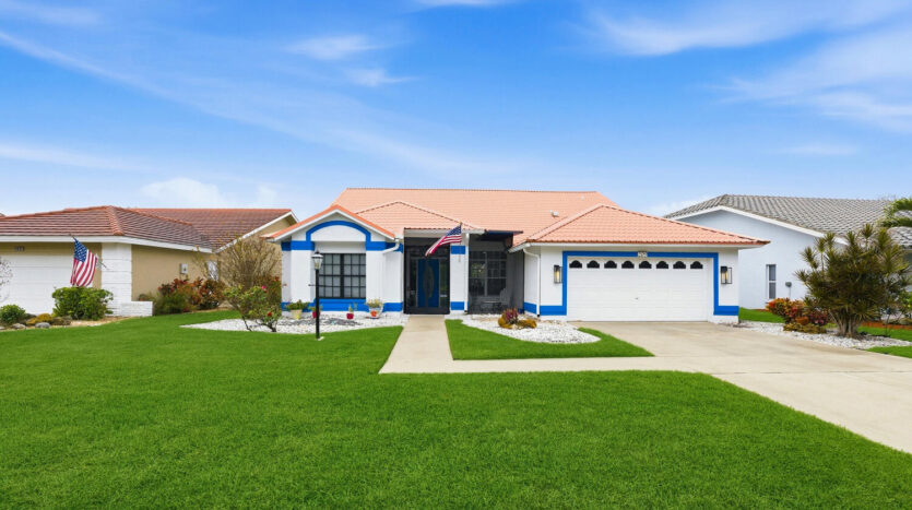 Single-story suburban house with a manicured lawn and blue accents.