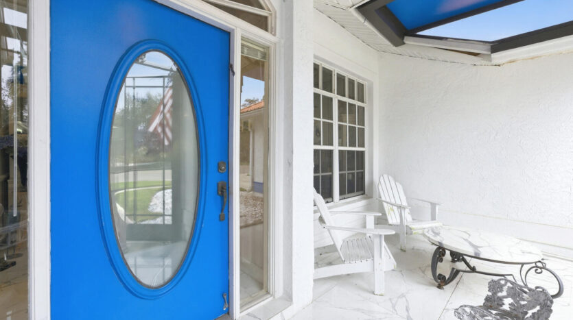Bright porch with a bold blue door and white rocking chairs.