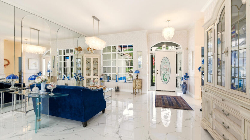 Elegant living room with blue velvet sofa and marble flooring.