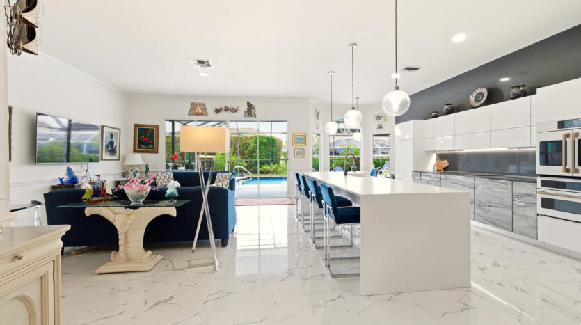 Bright, modern open kitchen and living room with white marble floors and blue accents.