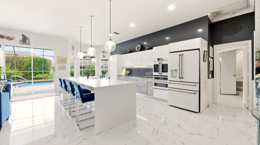Sleek modern kitchen with white marble countertops and blue bar stools.