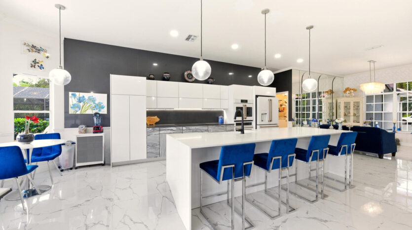 Modern kitchen with white cabinetry and blue bar stools.