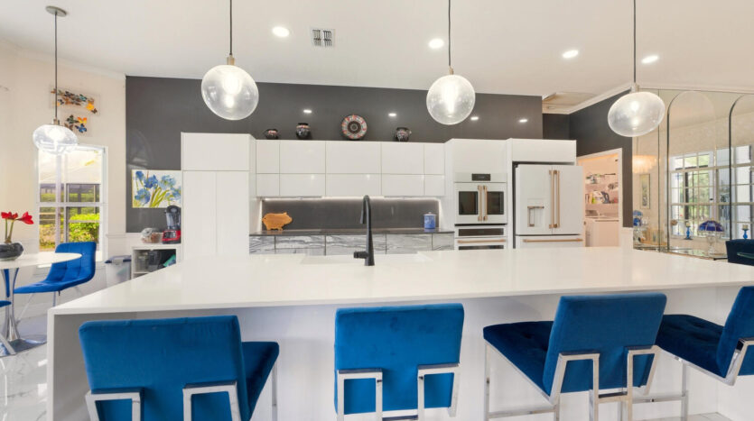 Modern kitchen with white countertops and blue bar stools.