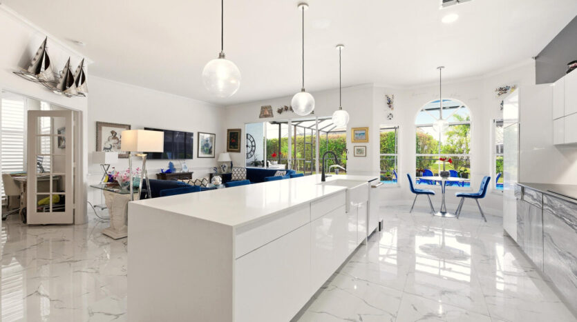 Modern white kitchen with sleek island and blue accents.
