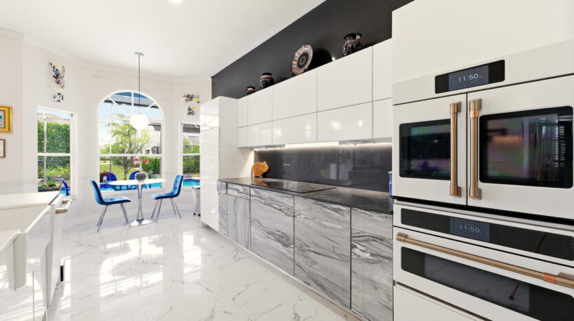 Modern kitchen with sleek black and white cabinetry and marble flooring.