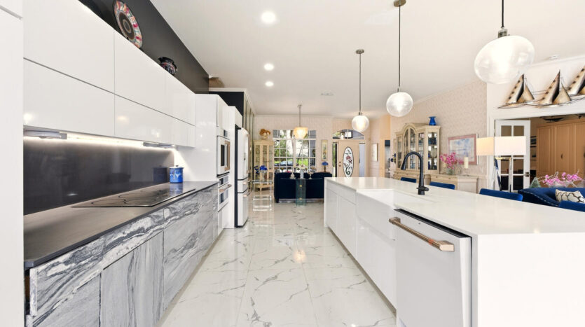 Modern kitchen with white cabinetry and marble flooring.