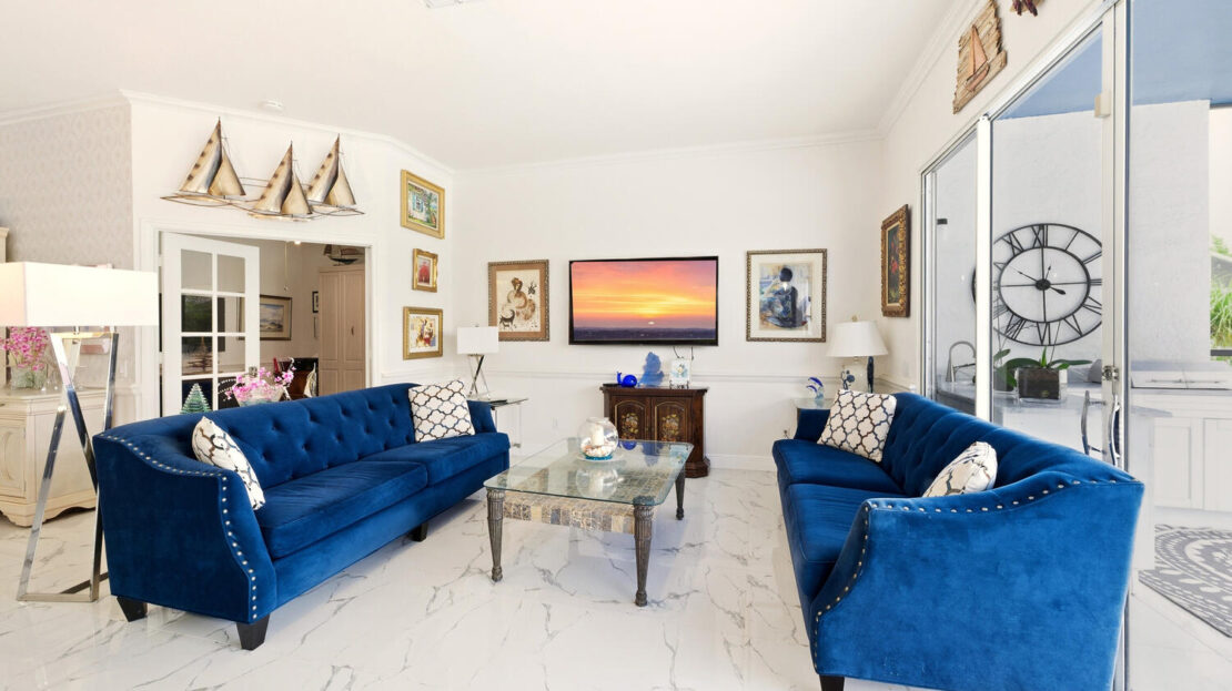 Elegant living room with blue velvet sofas and sunset artwork.