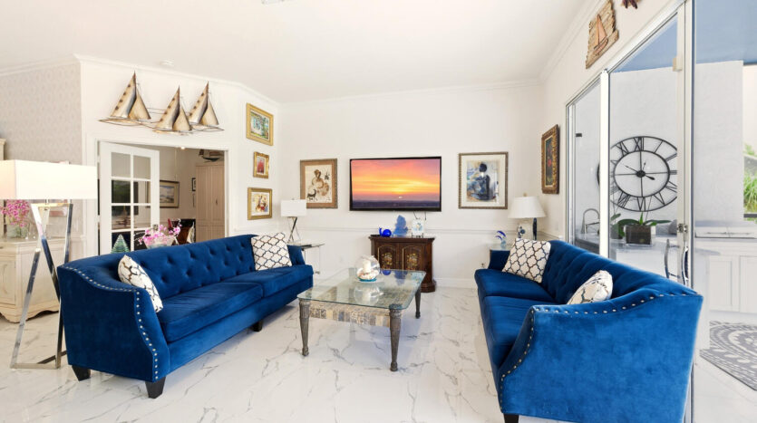 Elegant living room with blue velvet sofas and sunset artwork.