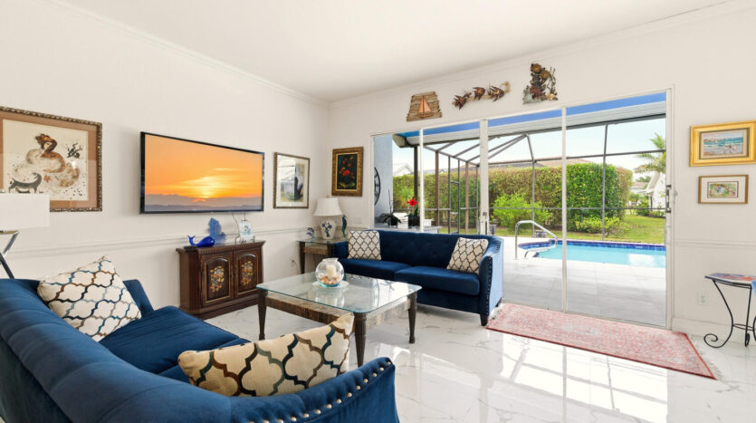 Elegant living room with blue sofas and a pool view through sliding glass doors.