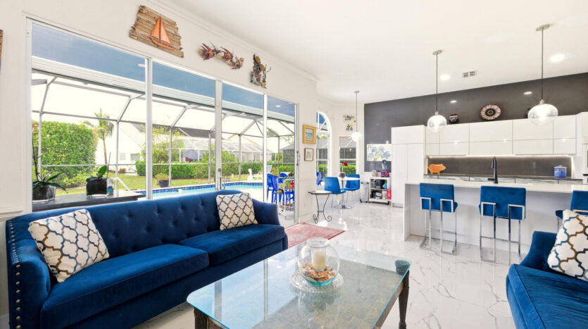 Bright modern living room with blue sofa and open kitchen.