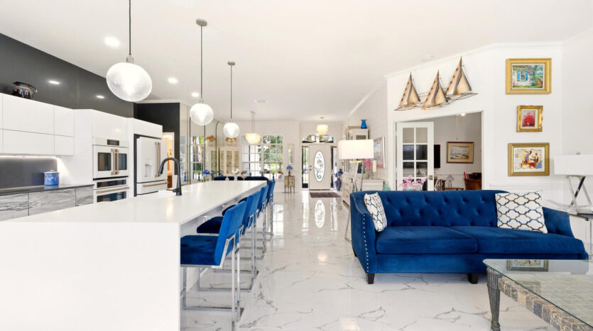 Spacious modern kitchen and living area with marble flooring and blue accents.