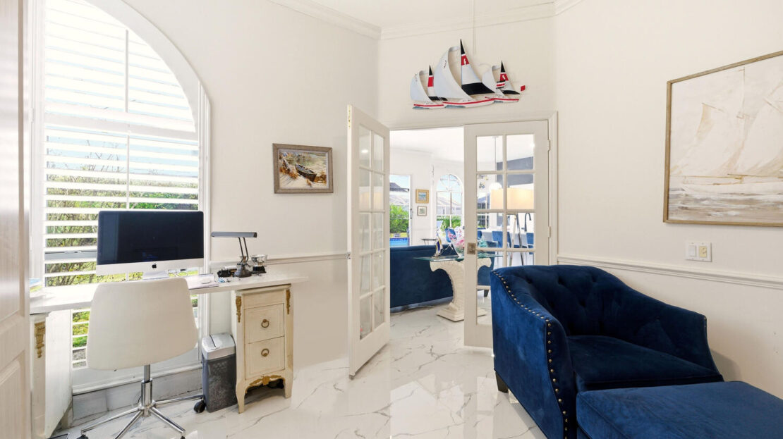 Bright, elegant living room with blue velvet sofa and marble floor.