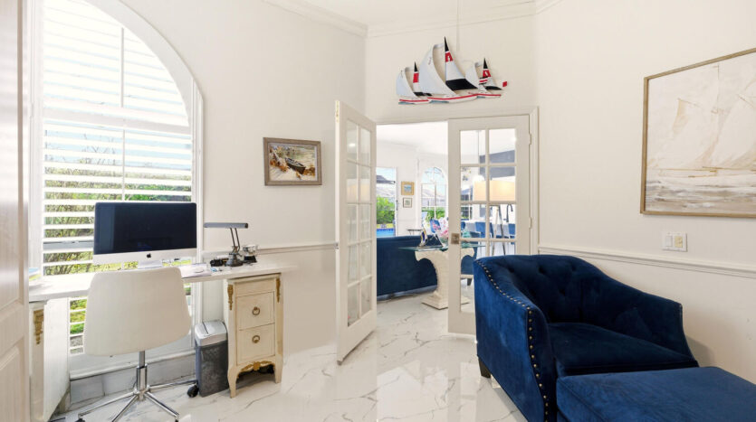 Bright, elegant living room with blue velvet sofa and marble floor.