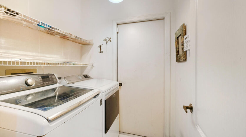 Compact laundry room with washer, dryer, and white walls.