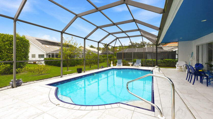 Bright outdoor swimming pool enclosed by a metal frame and screen.