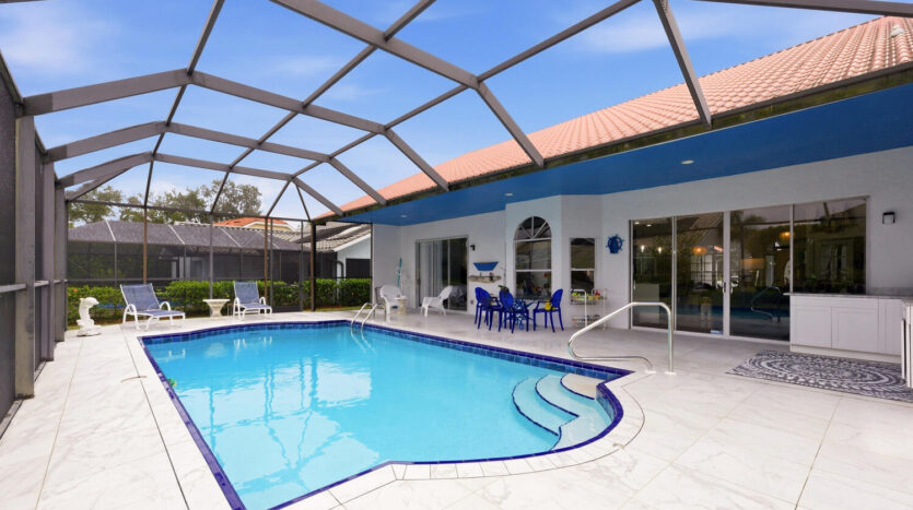 Modern backyard with a swimming pool and seating area under a screened enclosure.