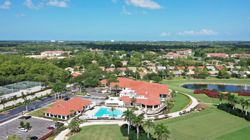 Aerial view of a luxurious golf club with pools and red-roofed buildings.