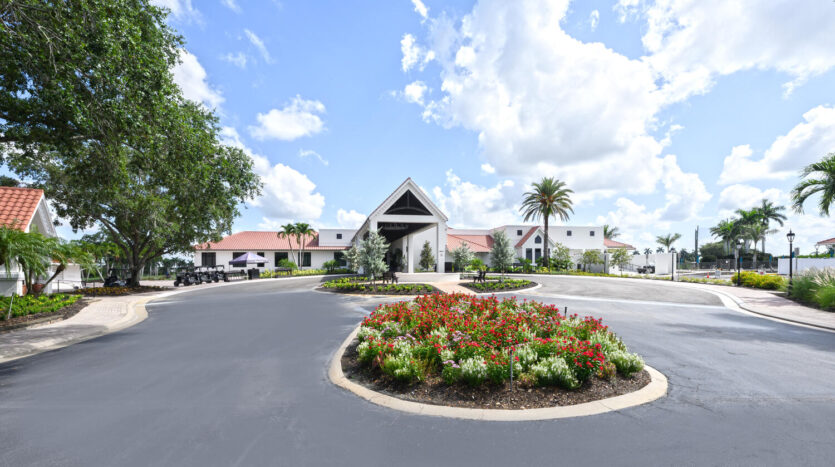 Entrance to a tropical resort with vibrant flowers and clear skies.